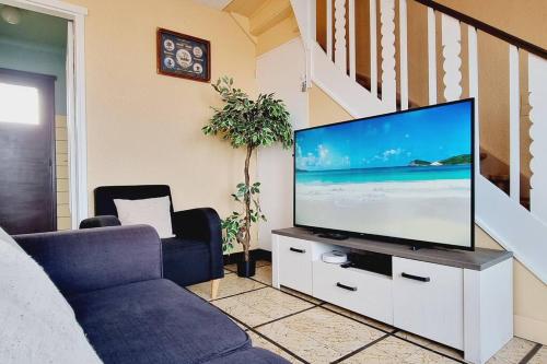 a living room with a flat screen tv on a cabinet at Maison des Marées - Digue de mer in Bray-Dunes