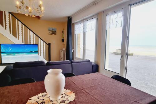 a vase on a table in a living room with a couch at Maison des Marées - Digue de mer in Bray-Dunes