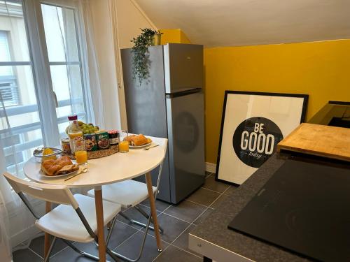 a kitchen with a table with food and a refrigerator at Appart' Studio cooconing - Champs Elysées - NETFLIX in Maisons-Laffitte