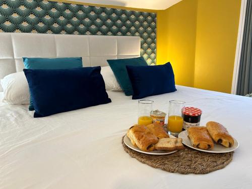 uma bandeja de pão e sumo de laranja numa cama em Appart' Studio cooconing - Champs Elysées - JO 2024 em Maisons-Laffitte