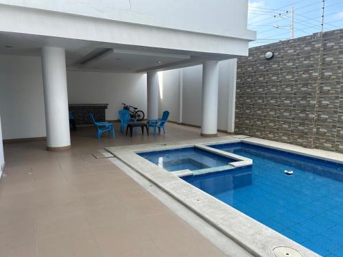 a swimming pool with blue chairs and a table at Kattyapartament Chipipe Salinas in Salinas