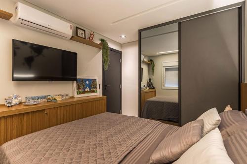 a bedroom with a bed and a flat screen tv at Apartamento Mundo in Guarujá