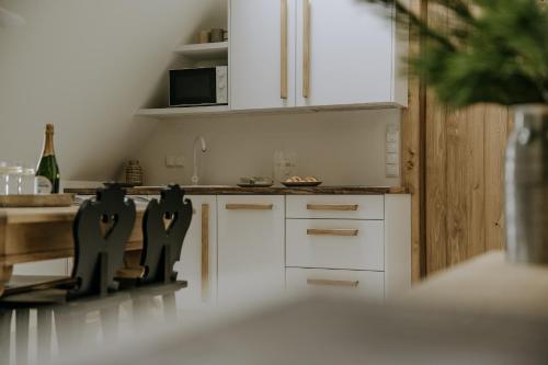 a kitchen with white cabinets and a table at Zakątek Krupówki - Apartamenty w Centrum in Zakopane