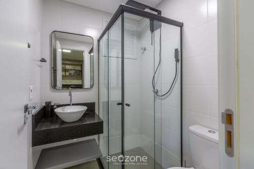 La salle de bains est pourvue d'un lavabo et d'une douche en verre. dans l'établissement Lindo apto 1 quarto em Joinville-SC MSE0302, à Joinville
