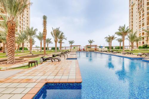 a pool with benches and palm trees and buildings at GLOBALSTAY. Luxury 3 Bedroom + Maid Townhouse with Sea View in Dubai