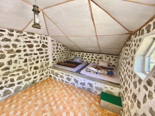 Zimmer mit einer Steinmauer und einem Bett in einem Zimmer in der Unterkunft Chumang River Nest in Thode