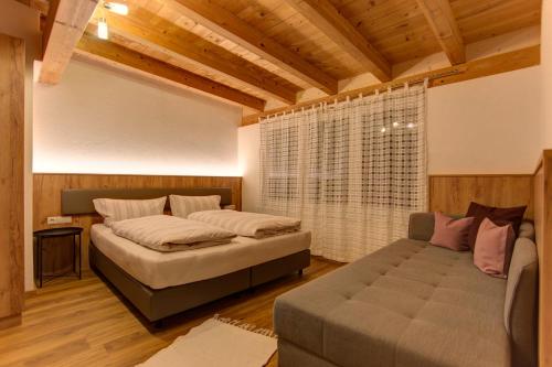 a bedroom with a bed and a couch and a window at Haus Mattle in Pettneu am Arlberg