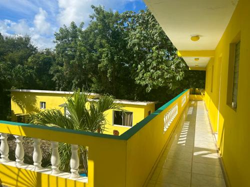 a balcony of a yellow building with trees in the background at Coco Hotel and Hostel in Sosúa