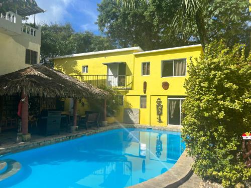 a pool in front of a yellow building at Coco Hotel and Hostel in Sosúa