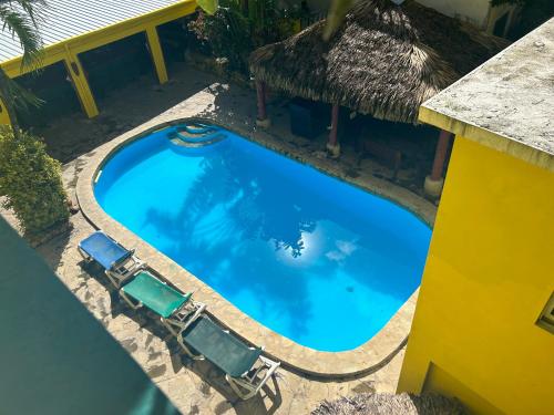 an overhead view of a swimming pool with chairs and a thatch roof at Coco Hotel and Hostel in Sosúa