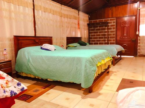 a bedroom with two beds with green comforter at Hospedaje Valentina para ti y tu familia in Mera
