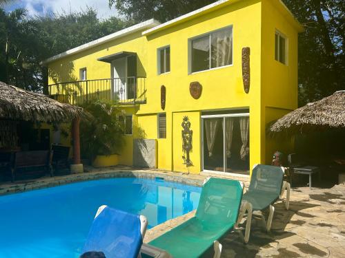 a yellow house with a pool and chairs in front of it at Coco Hotel and Hostel in Sosúa