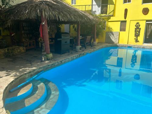 a swimming pool with a straw umbrella next to a building at Coco Hotel and Hostel in Sosúa