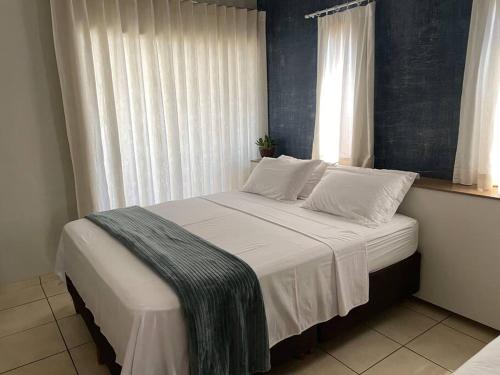 a bedroom with a bed with white sheets and a window at Casa conforto e estilo in Palmas