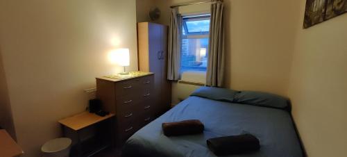 a bedroom with a bed and a dresser and a window at Upton Park - House in London