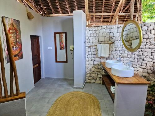a bathroom with two sinks and a mirror at Aya Beach Resort in Kizimkazi