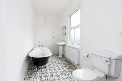 baño blanco con bañera, aseo y lavamanos en The Cleveland Way, North Yorkshire, en Loftus