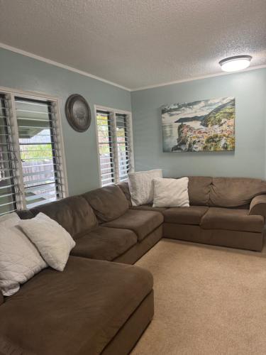 a living room with a brown couch and a clock at Tavares house king room in Waialua