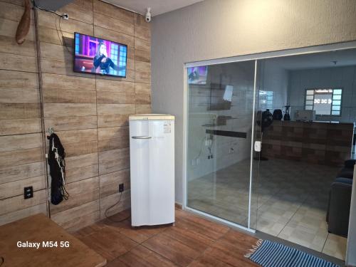 a white refrigerator in a room with a tv at Cantinho do Rafa São Lourenço MG in São Lourenço