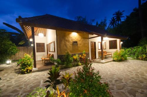 a small house with a patio at night at Si Pitung Village in Gili Air