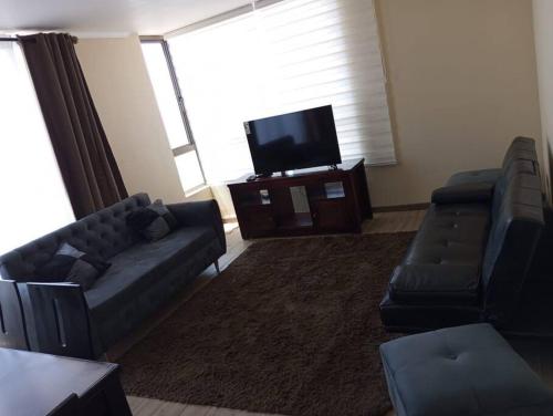 uma sala de estar com um sofá e uma televisão de ecrã plano em frente a la playa vista preciosa 3 habitaciones 2 baños em Iquique