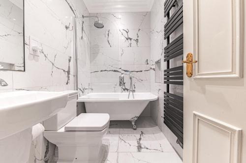 a white bathroom with a tub and a toilet and a sink at 1 Brathay Fell in Ambleside