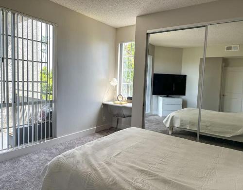 een slaapkamer met een bed, een spiegel en een televisie bij Hollywood Walk of Fame 1BR for Long Lease in Los Angeles