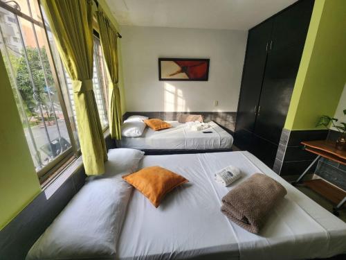 2 camas individuales en una habitación con ventana en Hotel Laureles Home, en Medellín
