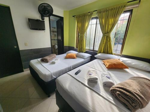 2 camas en una habitación con paredes amarillas en Hotel Laureles Home, en Medellín