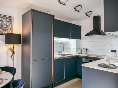 a kitchen with blue cabinets and a sink and a table at Stylish Retreat for Your Short Getaway in London
