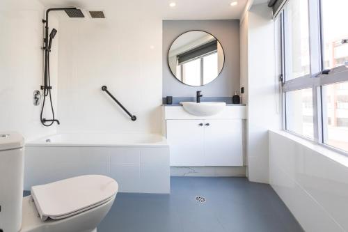 a white bathroom with a sink and a mirror at Gia Sydney in Sydney