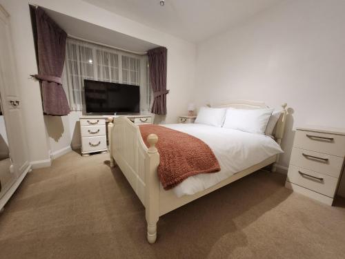 a bedroom with a white bed and a television at Elmdon House with 4 Spacious Bedrooms to choose in Birmingham
