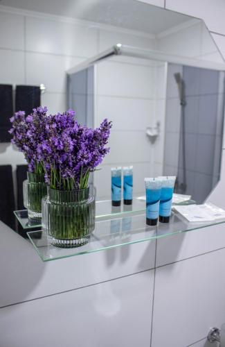 a glass counter with purple flowers in a mirror at Готельно-ресторанний комплекс Фамілія in Bushtyno