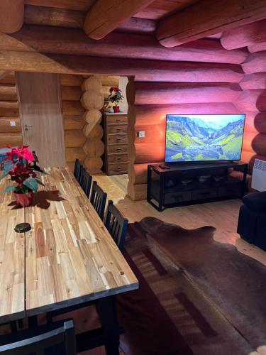 a living room with a table and a flat screen tv at Zrub Hanesy in Donovaly