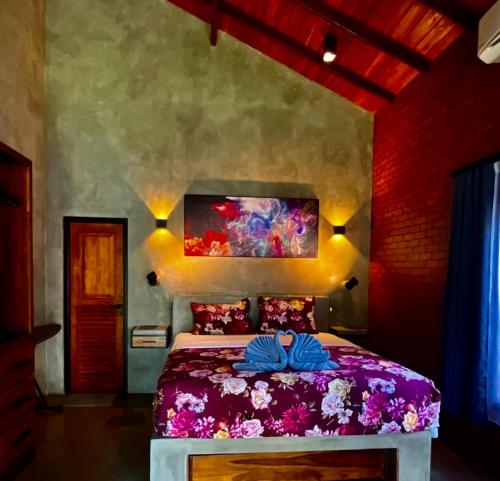 Negombo Morawala Beach Villa في نيجومبو: غرفة نوم بسرير ارجواني مع لوحة على الحائط
