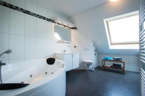 La salle de bains blanche est pourvue d'une baignoire et de toilettes. dans l'établissement Penthouse "Ostsee-Himmelreich" Großenbrode, à Großenbrode