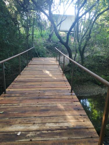 a wooden bridge over a river in a forest at Techos Amarillos aparthotel in Fomento