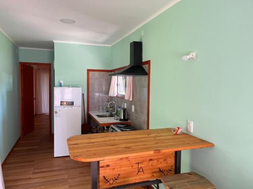 eine Küche mit einem Holztisch und einem Kühlschrank in der Unterkunft Techos Amarillos aparthotel in Fomento