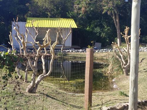 a fence with a yellow roof next to a pond at Techos Amarillos aparthotel in Fomento