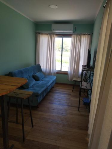 a living room with a blue couch and a window at Techos Amarillos aparthotel in Fomento