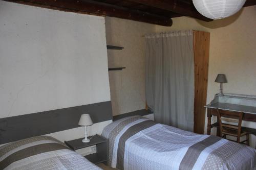 Un dormitorio con dos camas y una mesa y una ventana. en Gite Le Cantou, en Saint-Maurice-de-Lignon