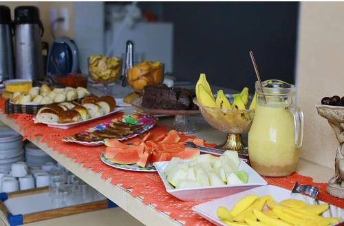 uma mesa coberta com pratos de alimentos e bebidas em Hotel Pousada Farol de Manaíra em João Pessoa