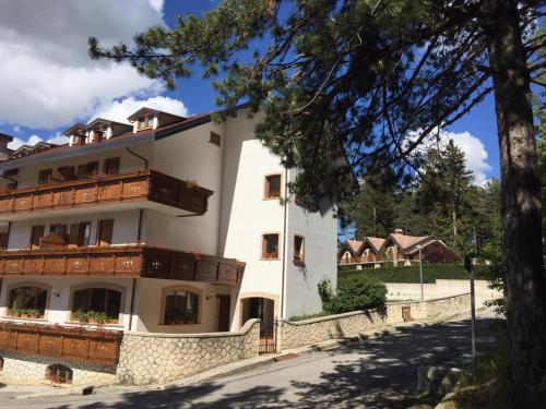 a white building with wooden balconies and a tree at HOTEL MILLE PINI in Ovindoli