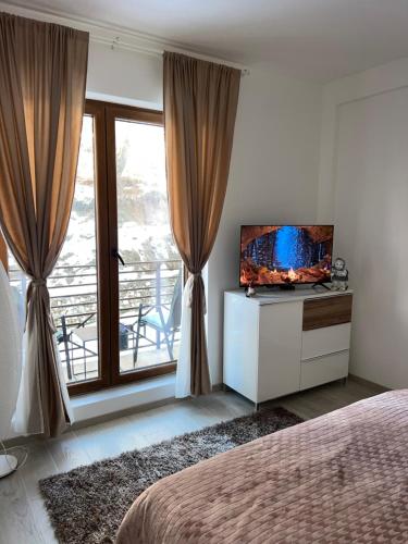 a bedroom with a television on a dresser with a window at Milmari N lux Sena in Kopaonik