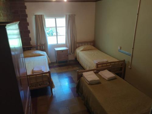 um pequeno quarto com 2 camas e uma janela em Casa El Encuentro em San Carlos de Bolívar