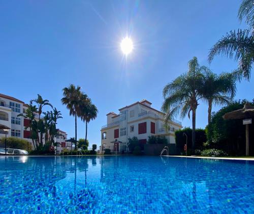 a large swimming pool with palm trees and a building at Mon paradis au soleil in Manilva