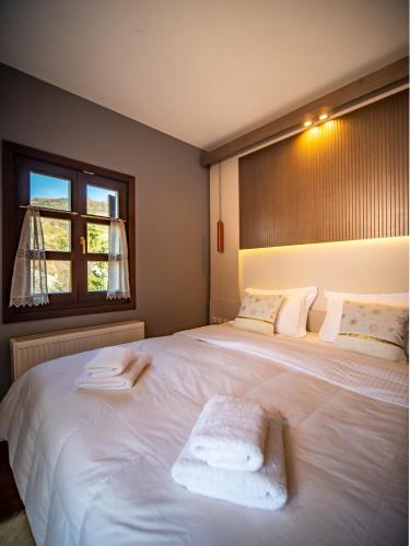 a bedroom with a large white bed with a window at Erofili Hotel & Suites in Portaria