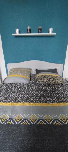- un lit avec deux oreillers et un mur bleu dans l'établissement Coquet 2 pièces proche de Paris, à Bagnolet