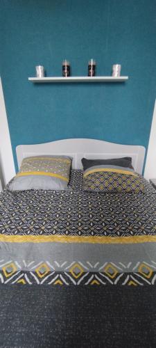een bed met 2 kussens en een blauwe muur bij Coquet 2 pièces proche de Paris in Bagnolet