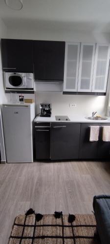 une cuisine avec des armoires noires et blanches et un sol dans l'établissement Coquet 2 pièces proche de Paris, à Bagnolet